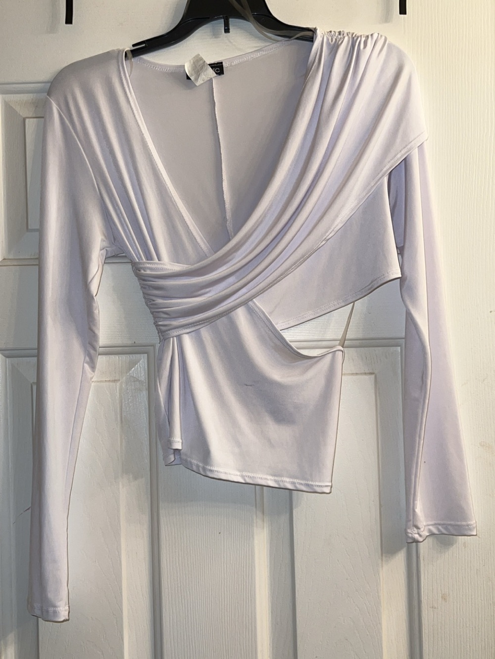 White long-sleeve top features a dramatic draped crossover front